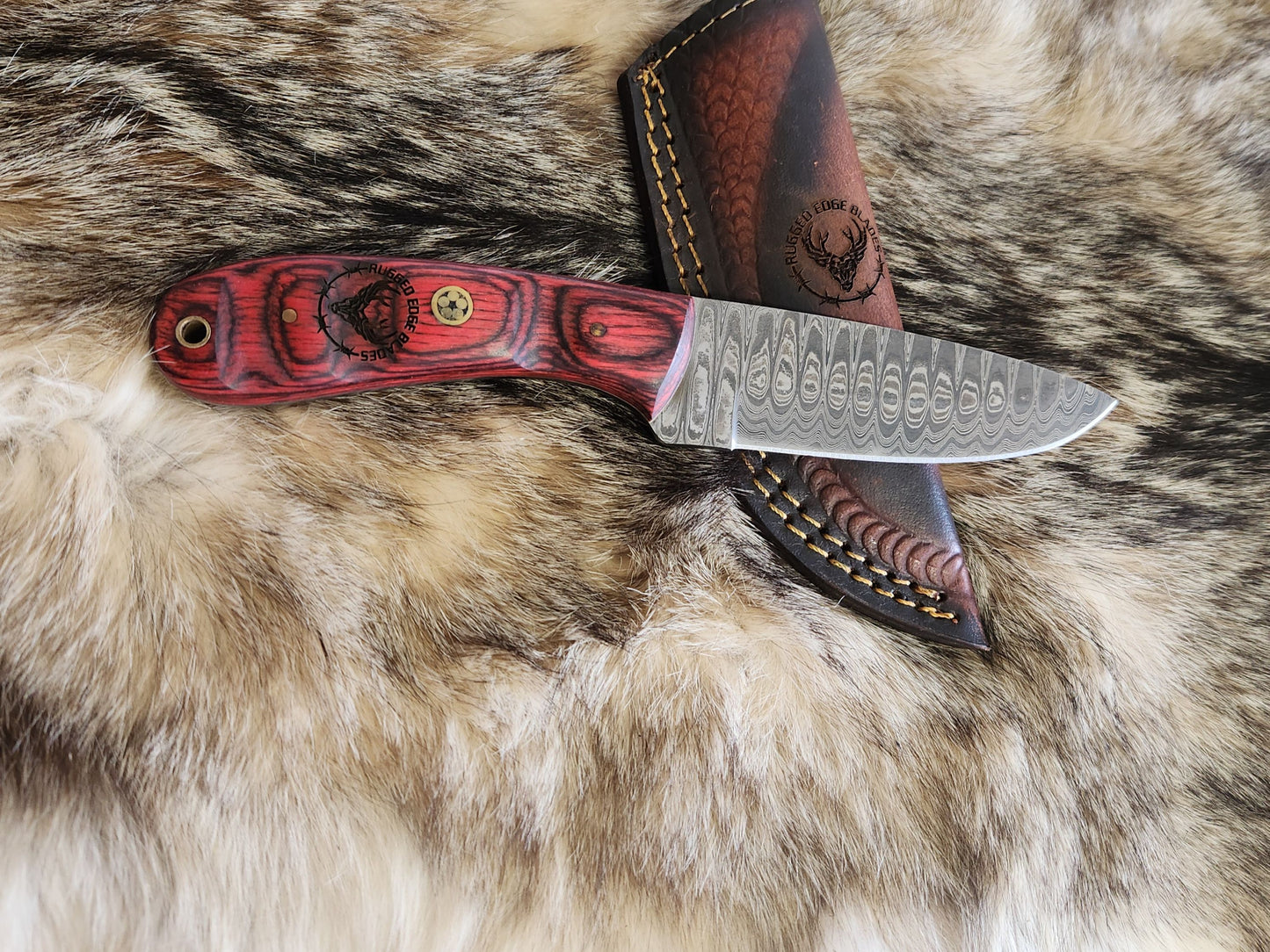 Carved Rosewood Handle Drop Style Knife with Damascus steel blade and engraved wood handle, displayed on fur with custom leather sheath. Ideal for camping and survival use.