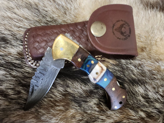 Walnut and Blue Stag pocket knife with Damascus steel blade, brass bolsters, and multicolored handle, displayed with leather sheath.