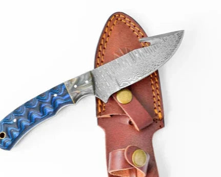 Damascus Steel Blue Wood Gut-hook & Skinning knife with patterned blade and ergonomic blue handle, displayed on a brown leather sheath.